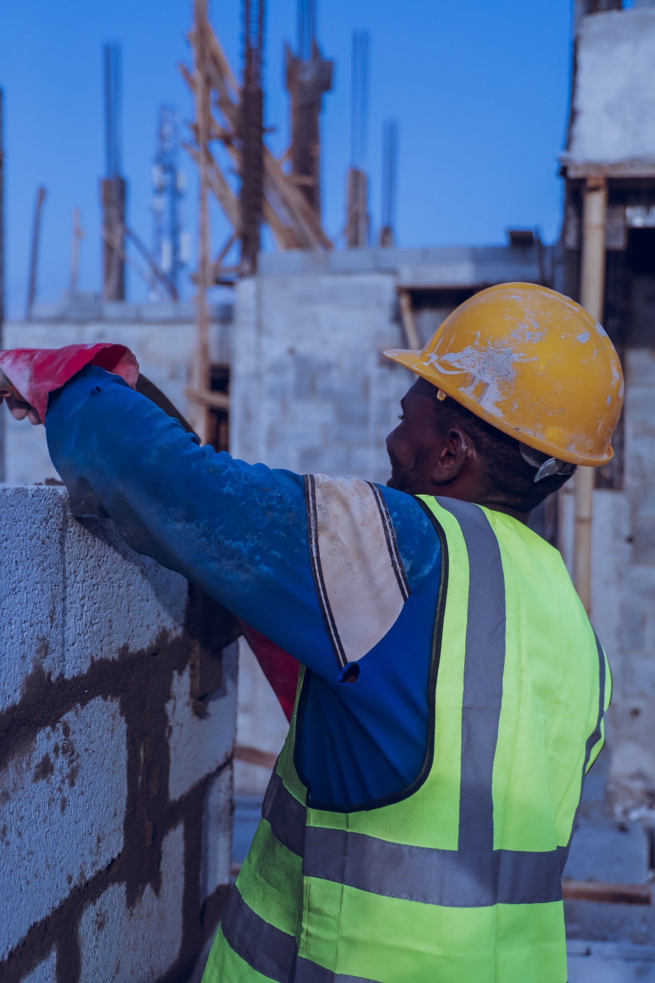 Essex builder in hi-vis vest and yellow hard hat laying blockwork on a new build extension - local SEO for builders by Click Boosters