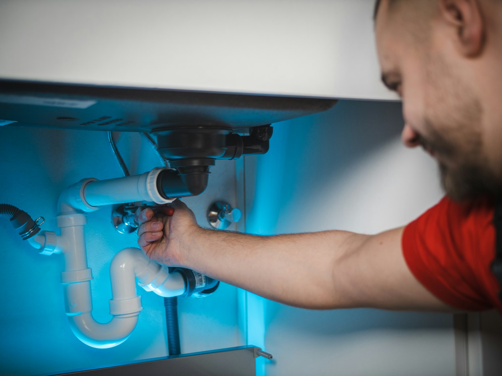 Close-up of a plumber's hands using a spanner on the copper pipework of a modern combi boiler installation