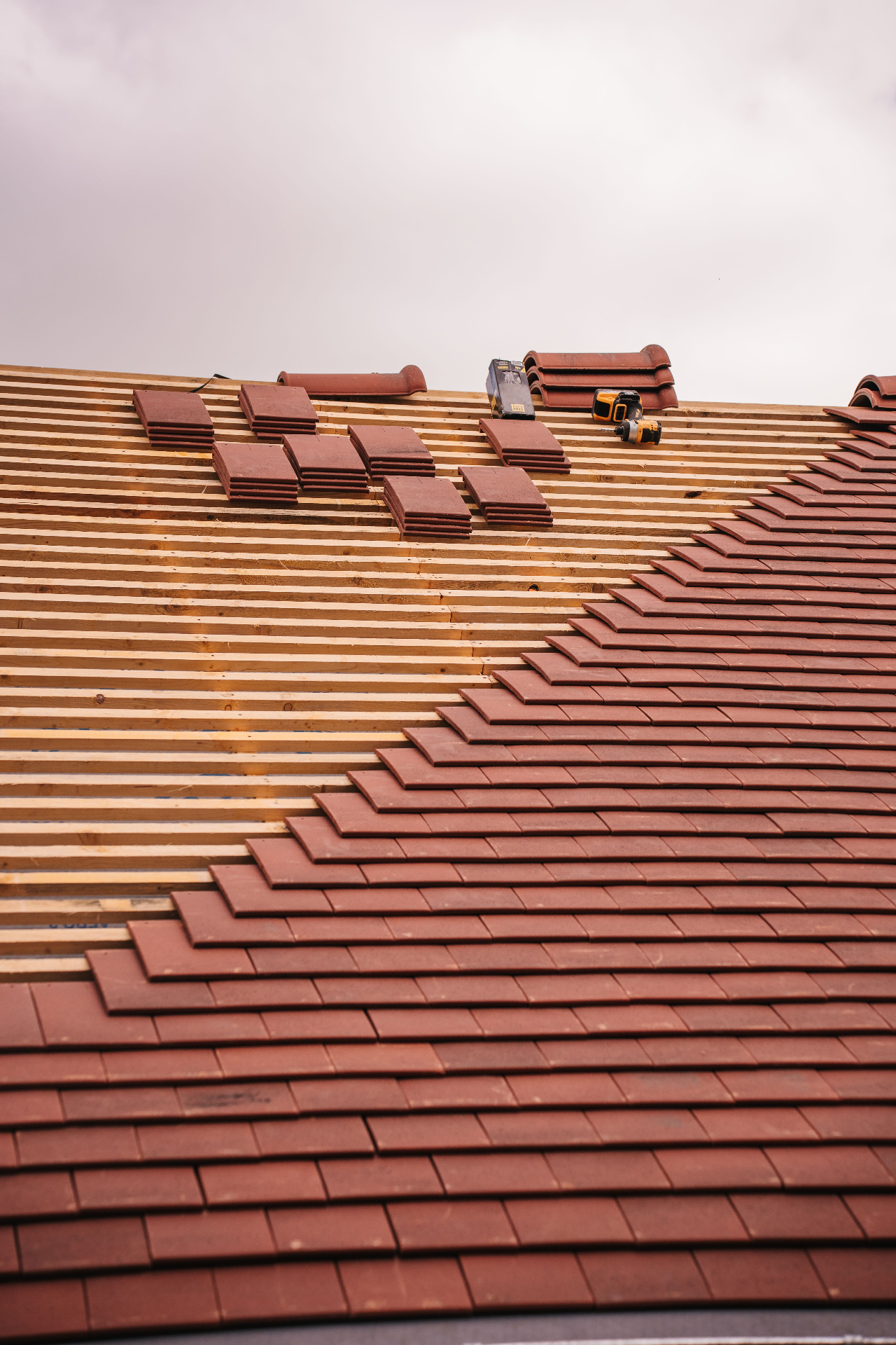 Pitched Essex re-roof in progress with new red clay tiles being laid on fresh timber battens and ridge tiles - local SEO for roofers by Click Boosters